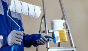 a professional carried two painting brushes in his hands to paint a house