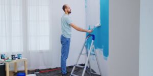 a man painting a house wall in white color