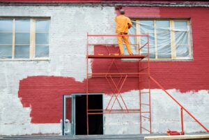 painter is painting a wall safely in red color