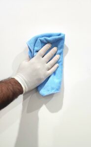 a person wearing glove is cleaning a white colored wall with a cloth
