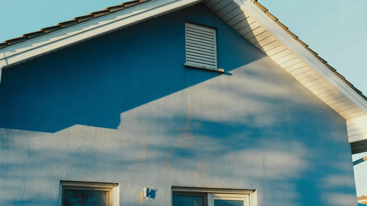 A blue house exterior with white trim, showing how to protect exterior paint from sun damage by using quality paint and proper maintenance.