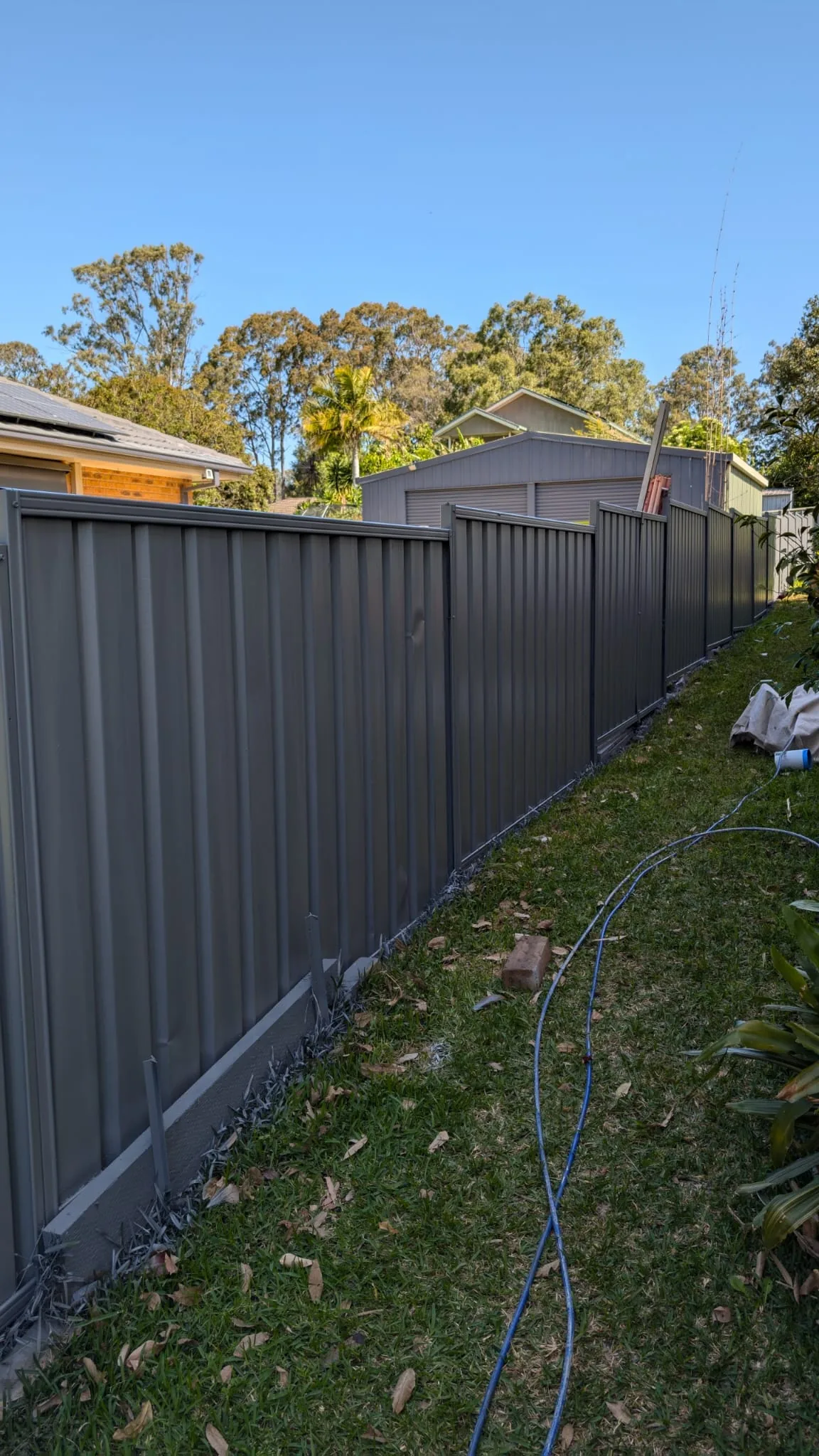 Metal boundary fence repainted in dark Monument at a Rothbury property.