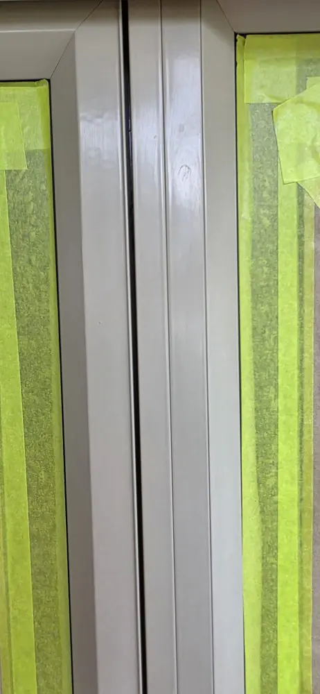 Freshly painted aluminium window frames with green masking protecting the glass