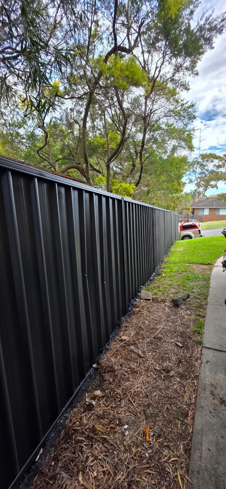 Street-side Colorbond fence painted Monument under gum trees