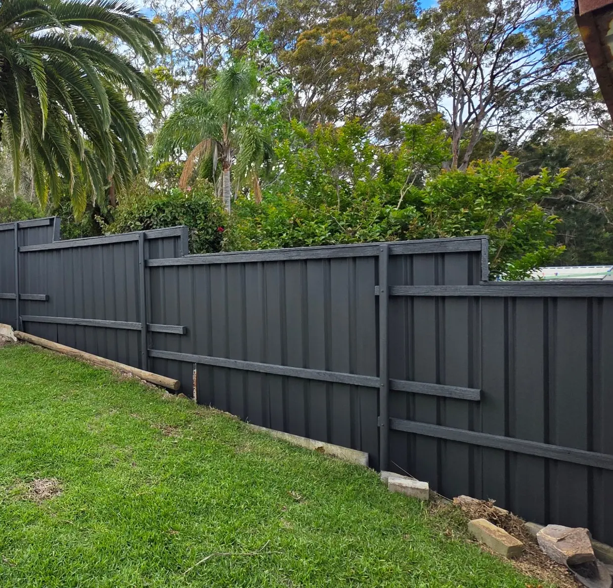 Backyard fence in Jewells painted Monument, with timber rails and a palm tree