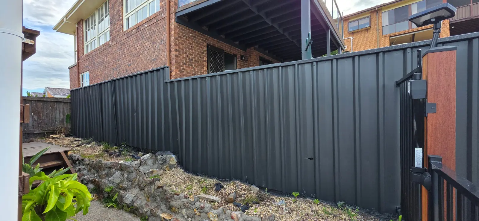 Fence beside a brick house in Jewells after painting in Colorbond Monument