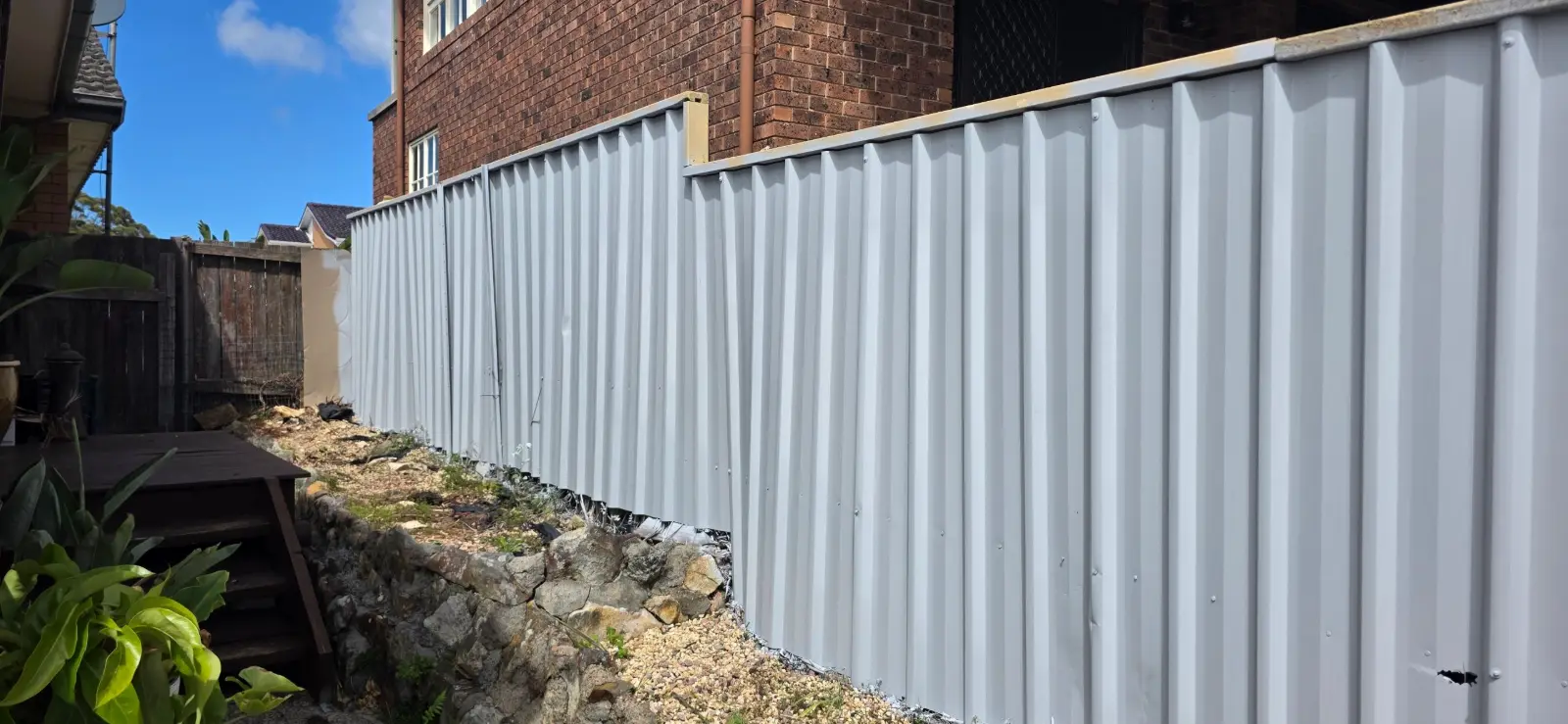 Galvanised fence panels beside a brick house after priming with Primecote