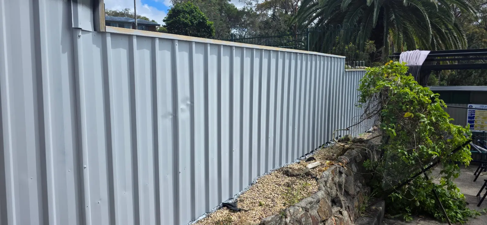 Galvanised fence panels primed with Globalcote Primecote above a stone retaining wall
